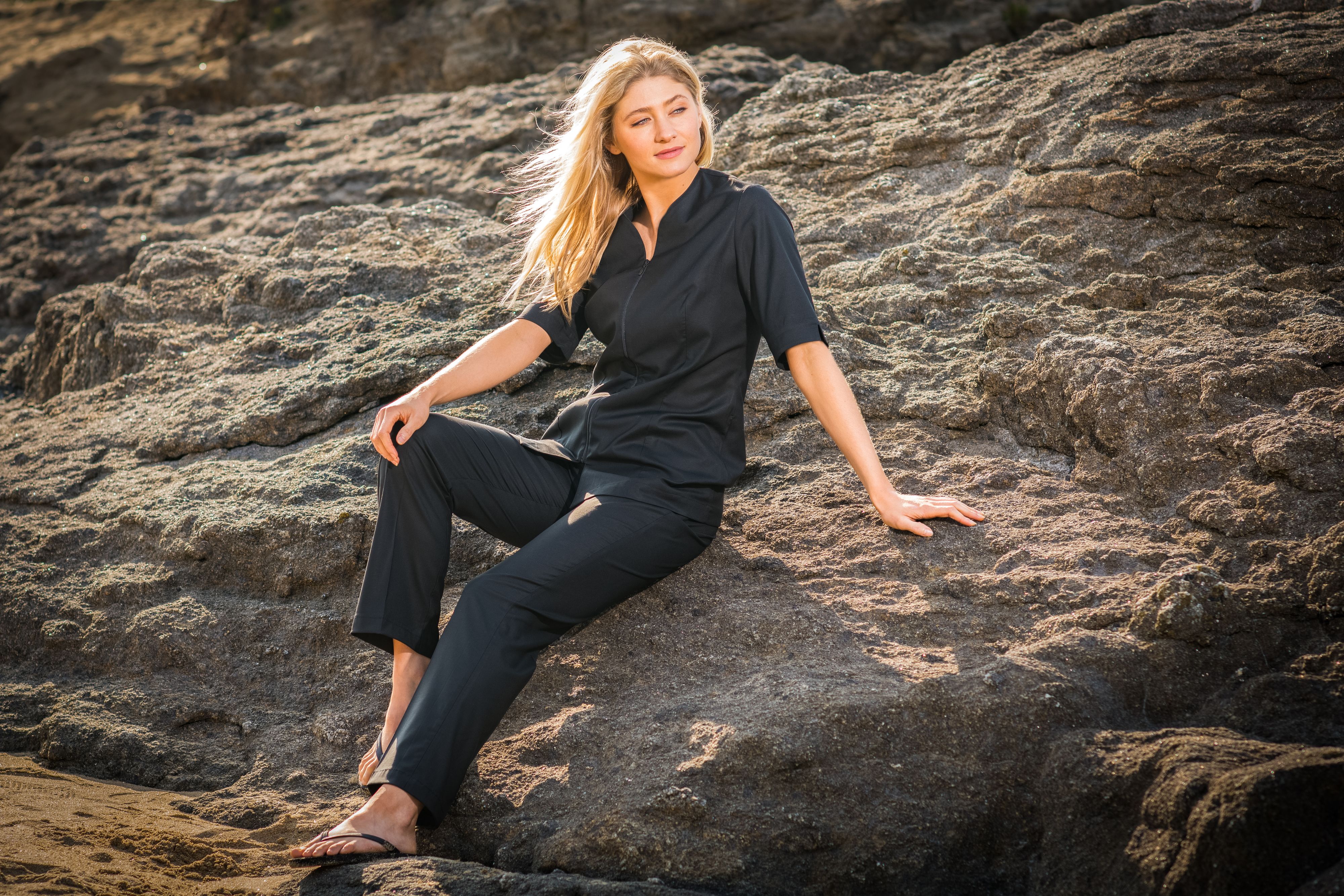 Blonde model wearing black sitting on rock in St. Malo  France
