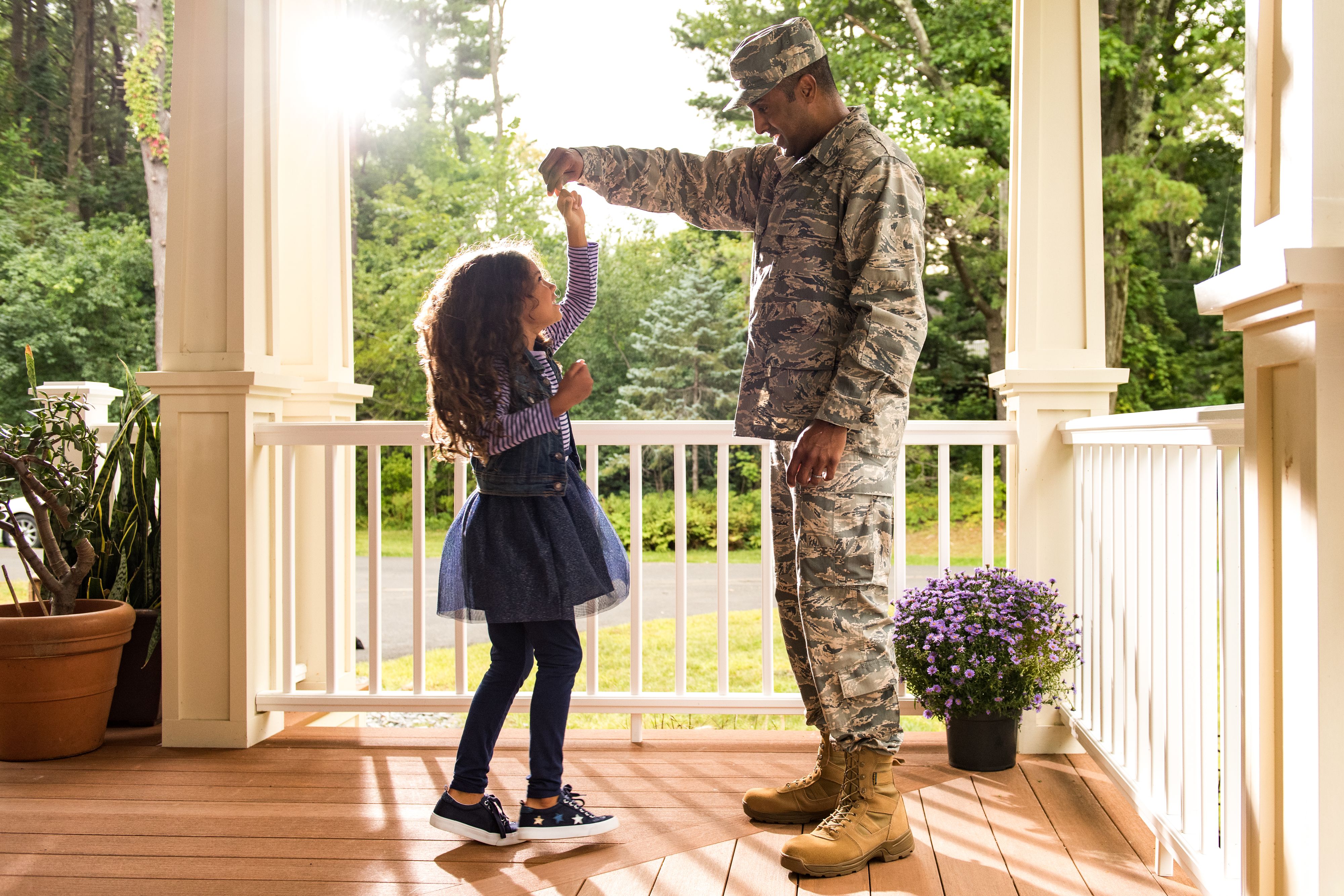 Soldier holds hand of daughter dancing on porch