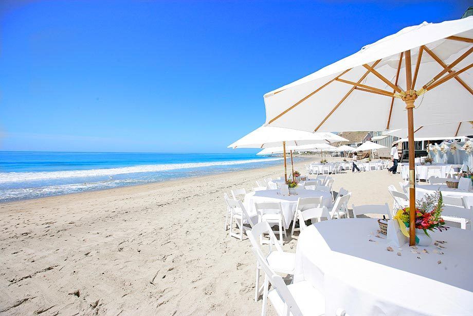 White tables on the sand at the Malibu beach house for the wedding of Monica and Randy.