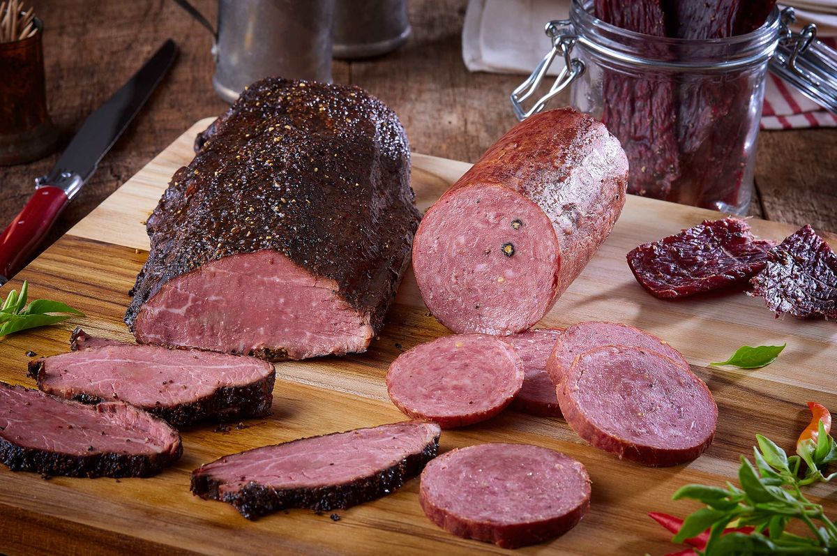 Ranch House mesquite smoked beef, summer sausage, and beef jerky arranged together on a wood board