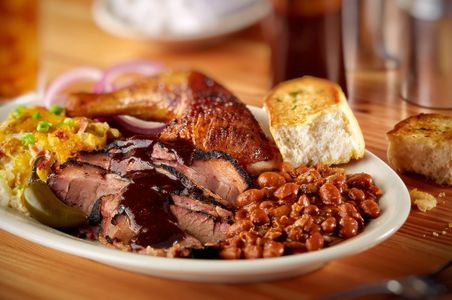 Bone Daddy's barbecue plate with sauced brisket, smoked chicken, baked beans, and Texas toast in Dallas, Texas
