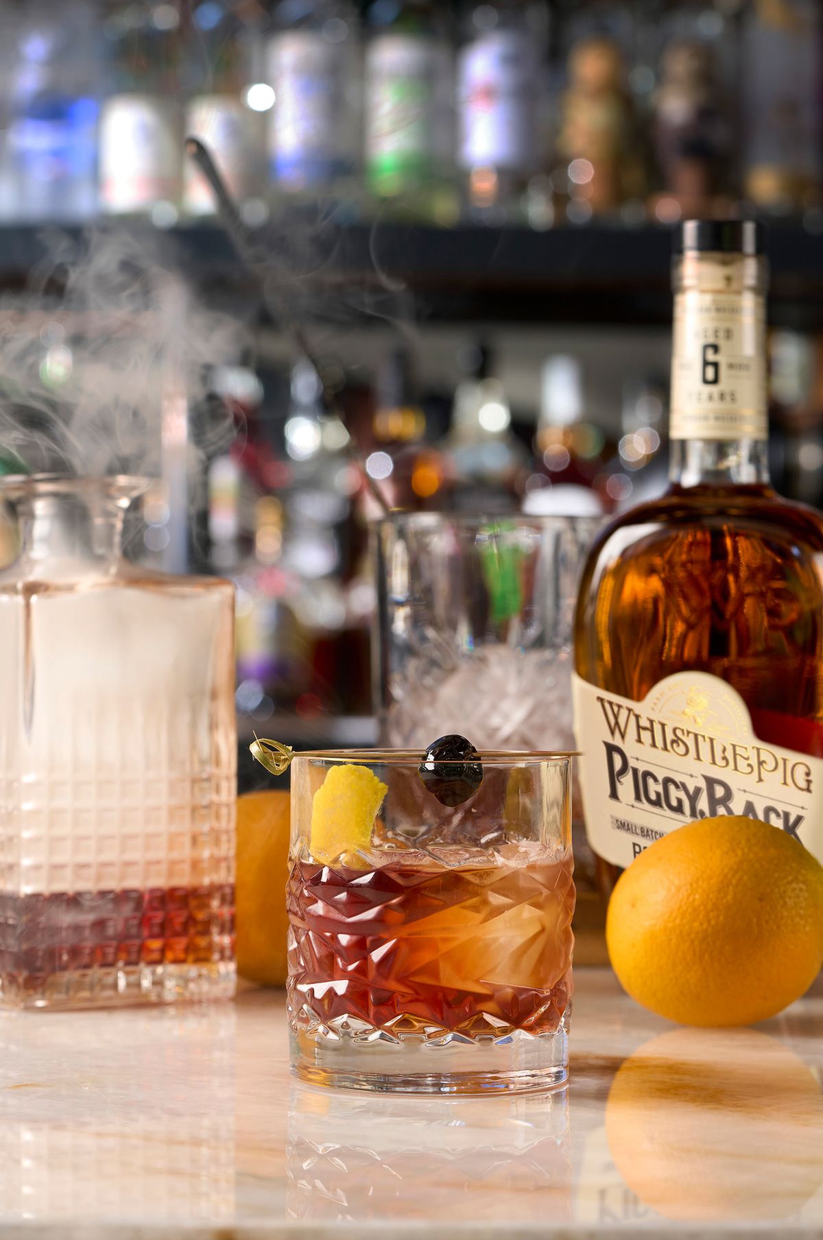 Smoked old fashioned in a cut crystal rocks glass with orange peel and brandied cherry, poured with WhistlePig PiggyBack rye at Sauce & Vine