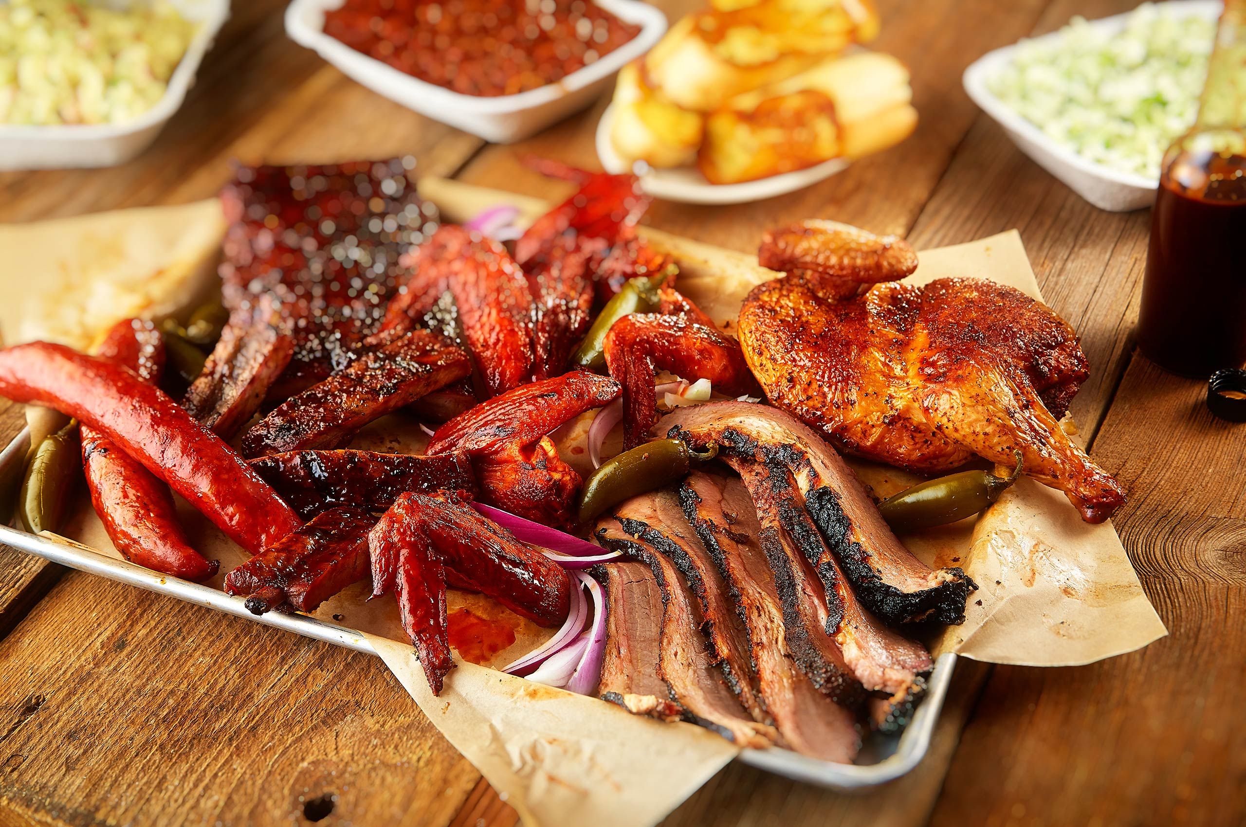 Bone Daddy's barbecue tray with smoked sausage, ribs, wings, brisket, and half chicken on butcher paper in Dallas, Texas