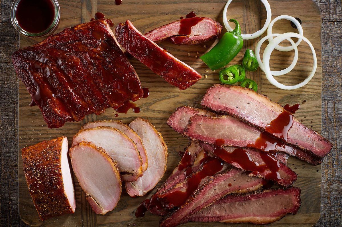 Overhead board of Ranch House mesquite smoked ribs, sliced turkey, and sauced brisket with jalapeño and onion