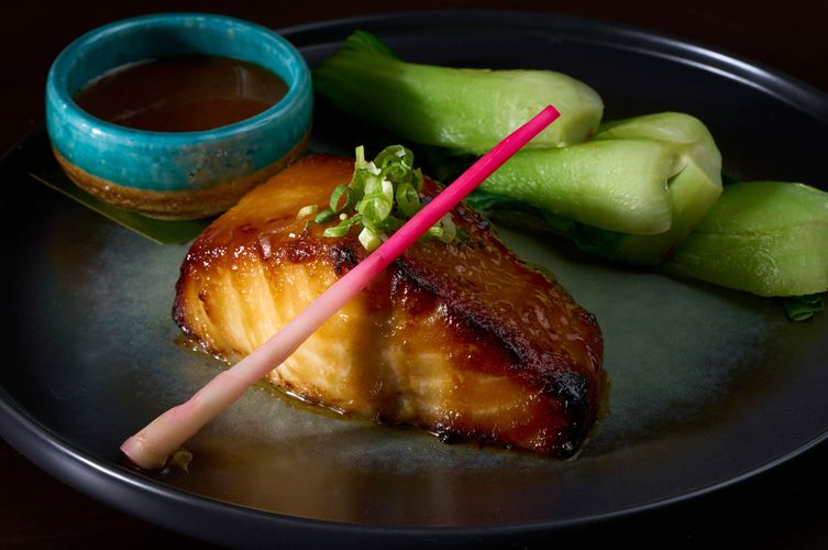 Miso-glazed black cod with baby bok choy and scallions on a dark ceramic plate at Soy Cowboy in Arlington, by a Dallas food and interiors photographer
