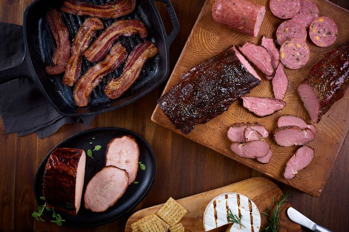 Overhead Ranch House Mesquite Smoked Meats spread with bacon in a cast iron pan, summer sausage, smoked beef, and ham