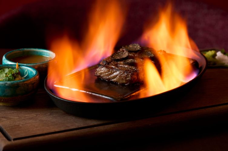 Flame-seared steak topped with shaved truffle on a cast-iron plate at Soy Cowboy in Arlington, tableside fire presentation, by a Dallas food photographer