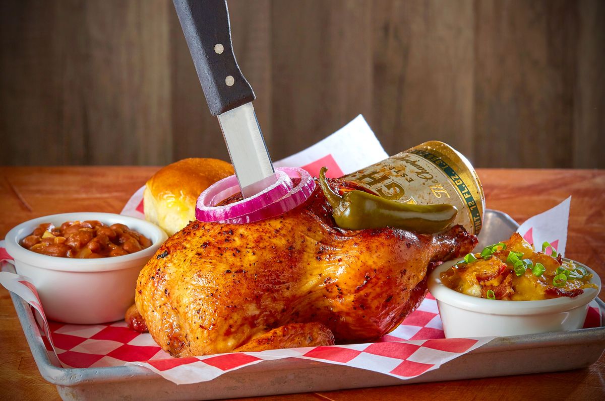 Bone Daddy's beer can chicken served in a checkered basket with baked beans, cheesy potatoes, and a roll in Dallas, Texas