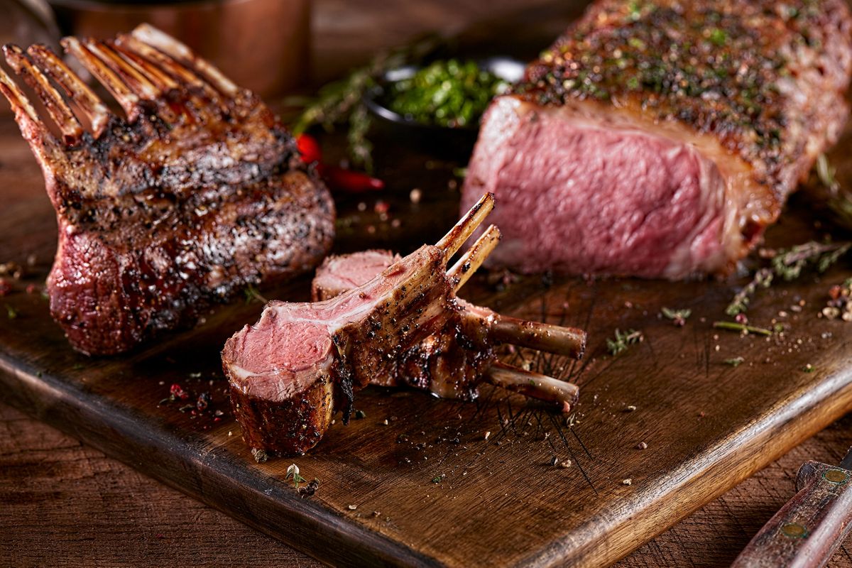 Fogo de Chão frenched rack of lamb carved beside an herb-crusted roast with chimichurri