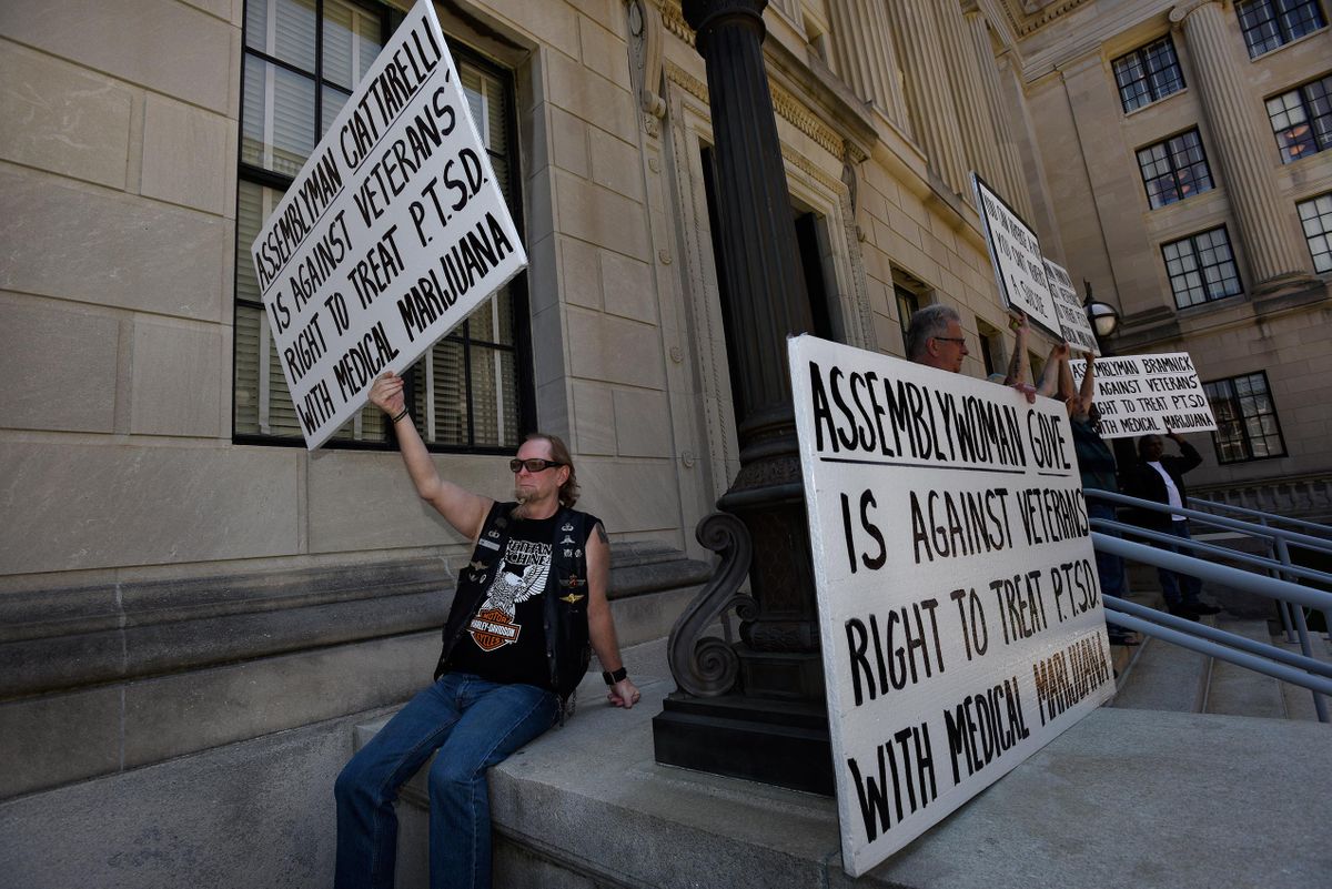 Don Karpowich holds up a sign as he protests to have PTS added to the list of conditions that can be treated with medical marijuana in NJ, as he and others protest at the State House. Protest