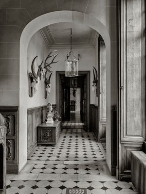 Inquire to acquire official limited edition black and white fine art prints of the historic gallery corridor at Château de Breteuil by William Curtis Rolf. William Curtis Rolf black and white photography Chateau de Breteuil gallery corridor checkered marble floor hunt trophies France Noble Houses Portfolio