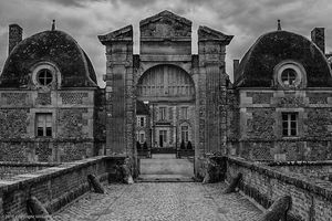 Inquire to acquire official limited edition black and white fine art prints of the historic entrance archway and bridge at Château de la Ferté-Saint-Aubin by William Curtis Rolf. William Curtis Rolf black and white photography Chateau de la Ferte Saint Aubin entrance archway bridge moat France Noble Houses Portfolio