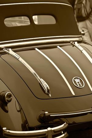 Fine-art sepia tone vertical photograph by William Curtis Rolf capturing the dark rear tail, polished chrome trim stripes, and crowned logo emblem of a vintage pre-war Horch cabriolet. Pebble Beach Dark Horch 853 Cabriolet Rear Trunk Sepia Print
