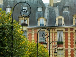 Color architectural photograph of a red brick facade with cream stone accents, steep slate roofs, and iron street lights at Place des Vosges in Paris by William Curtis Rolf. Place des Vosges Paris Red Brick Facade Color Print William Curtis Rolf