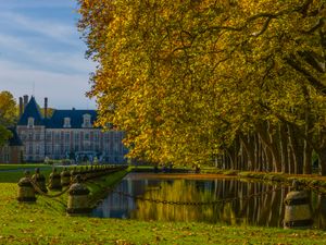 Color landscape photograph of the Grand Canal lined with vibrant autumn trees at Chateau de Courances in France by William Curtis Rolf. Chateau de Courances Front Canal Autumn Color Print
