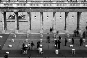 Black and white horizontal architectural photograph of striped columns with blurred moving figures and classical columns at Palais-Royal by William Curtis Rolf. Palais Royal Paris Colonnes de Buren Study 3 Black and White Print William Curtis Rolf