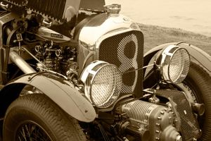 Fine-art sepia tone photograph by William Curtis Rolf from a right-rear angle showing large vintage headlights and the exposed engine compartment of a pre-war Bentley. Pebble Beach Vintage Bentley Exposed Engine Sepia Print