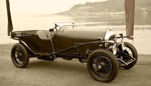 Fine-art sepia tone photograph by William Curtis Rolf capturing a left-rear perspective of a very early pre-war roadster featuring long body panels and ultra-narrow wire wheels. Pebble Beach Early Pre War Roadster Wire Wheels Sepia Print