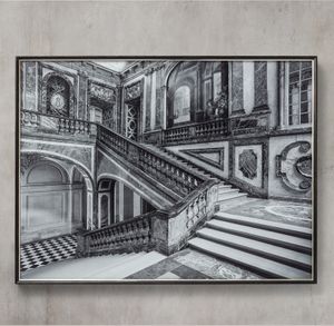 William Curtis Rolf's carefully selected viewpoint from the first landing of L'Escalier de la Reine (Queen's Staircase) at the Château de Versailles brings together the sweeping marble balustrades, intersecting flights of stairs, and richly ornamented walls in a striking composition that reveals the architectural complexity of this historic French royal interior. William Curtis Rolf: Versailles Escalier de la Reine — Queen's Staircase (Black & White)