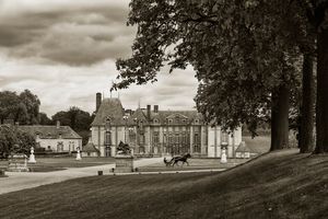 Sepia architectural view of Château de Grosbois, France, featuring a trotter and sulky passing the exedra. Photographed by William Curtis Rolf, the image highlights the contrast between classical French aristocratic architecture and modern equine sport. Sepia architectural view of Château de Grosbois, France, with a trotter and sulky passing the exedra.