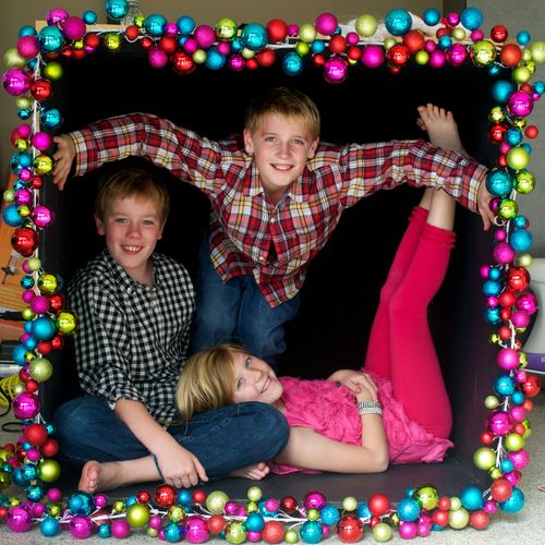 Two brothers and their sister crammed comfortably in a black box siblings