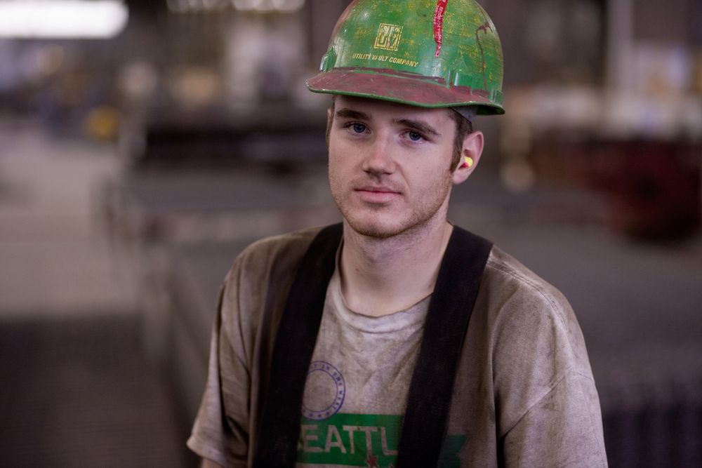 portrait of young male factory worker in a green hardhat