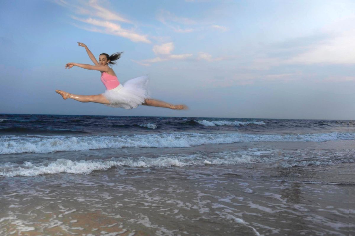 Ballerina leaping on beach