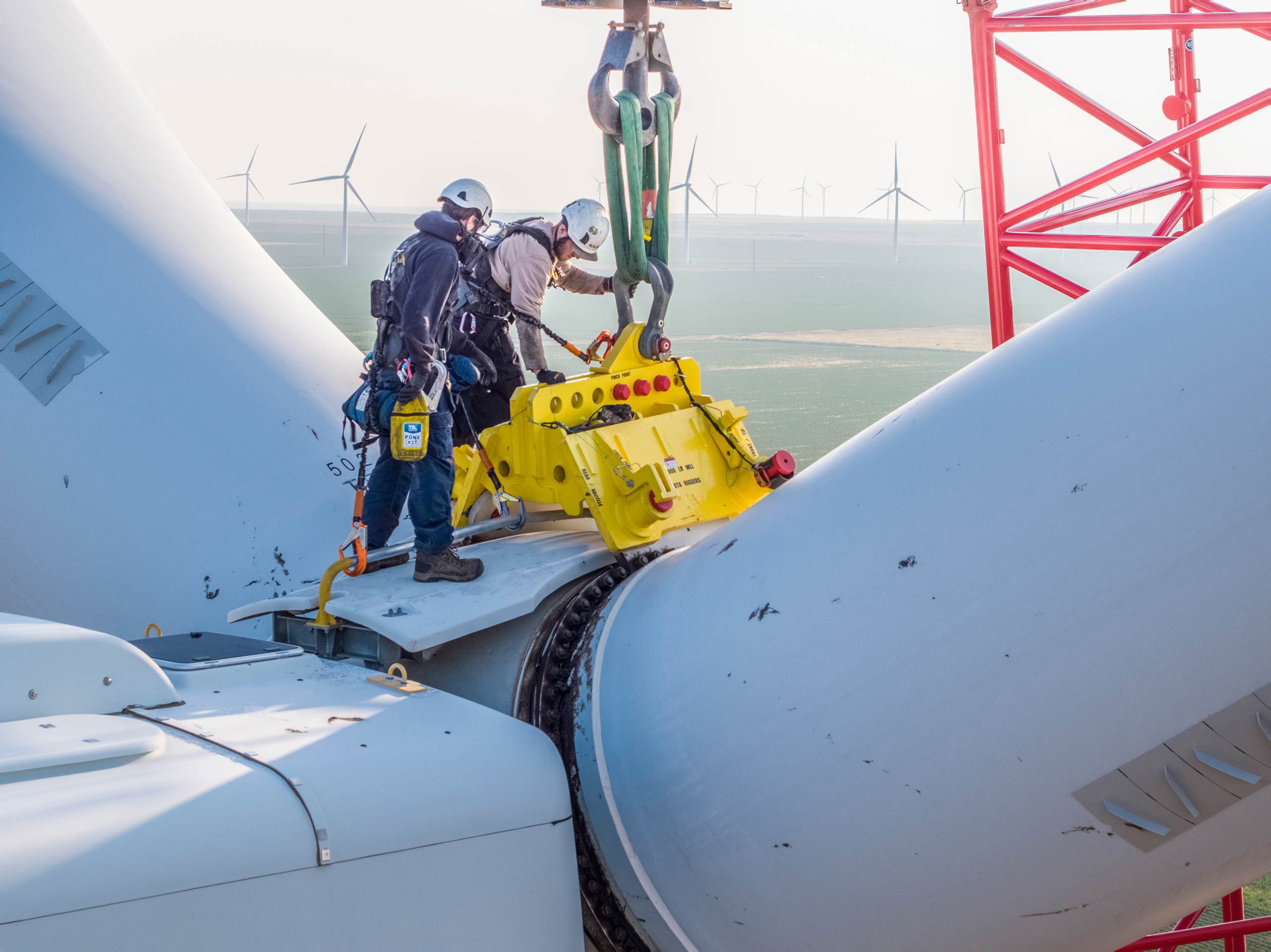Aerial photo of a wind turbine technician preparing to remove blades, showcasing expertise in renewable energy maintenance. Drone Aerial of Wind Turbine Technician - Blade Removal Prep