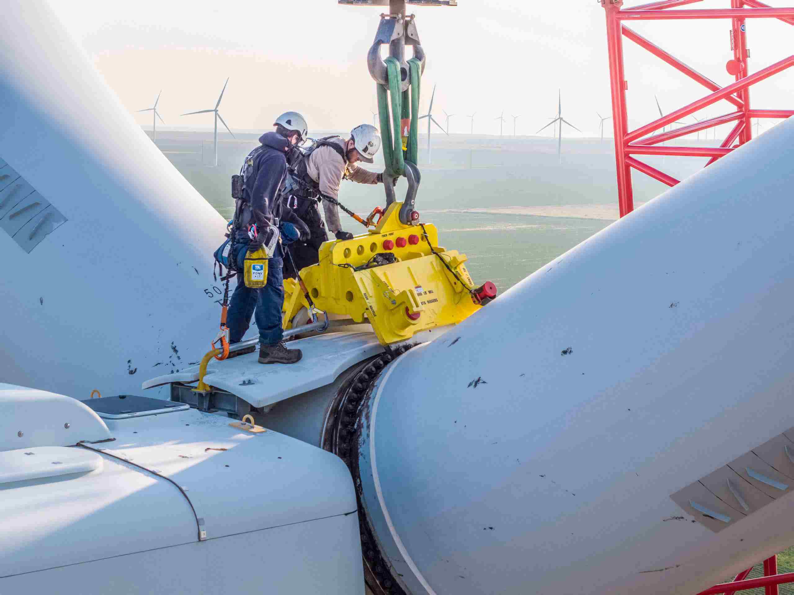 Aerial photo of a wind turbine technician preparing to remove blades, showcasing expertise in renewable energy maintenance. Drone Aerial of Wind Turbine Technician - Blade Removal Prep