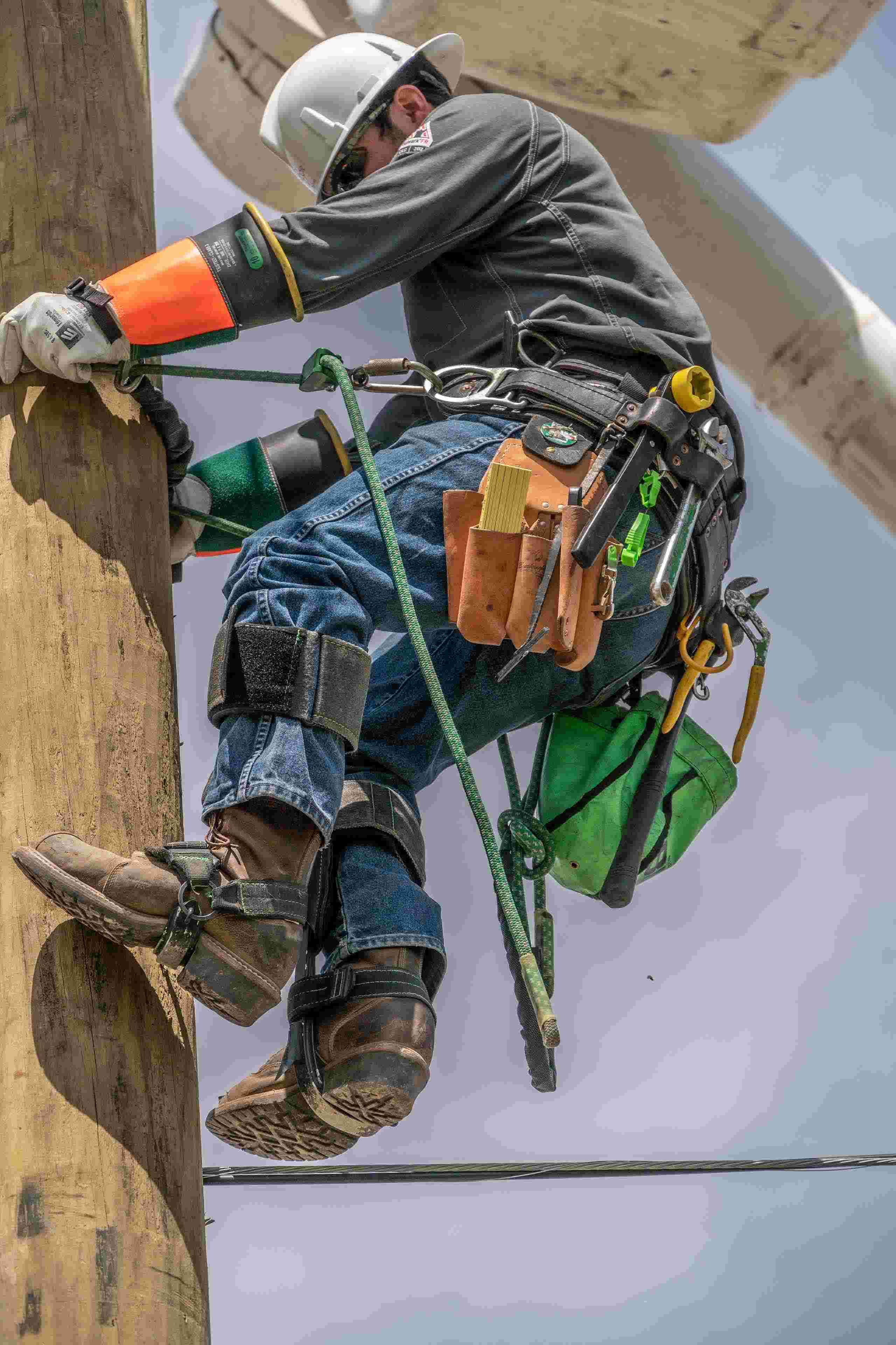 A dynamic photograph of a lineman climbing a telephone pole, expertly captured by a professional specializing in industrial photography in Dallas. This image showcases the lineman's skill and bravery as he performs essential maintenance work high above the