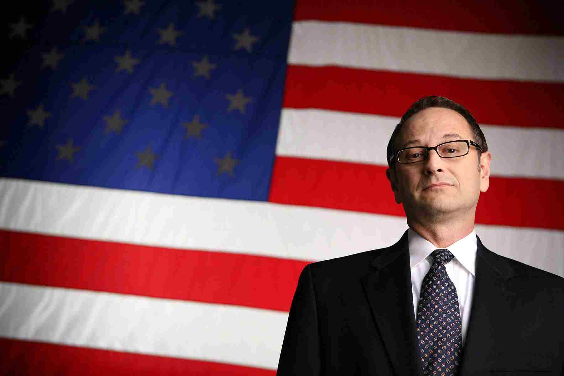 Corporate portrait of a VA doctor standing in front of an American flag, emphasizing professionalism and commitment to healthcare. VA Doctor Portrait with American Flag - Dallas Corporate Photography