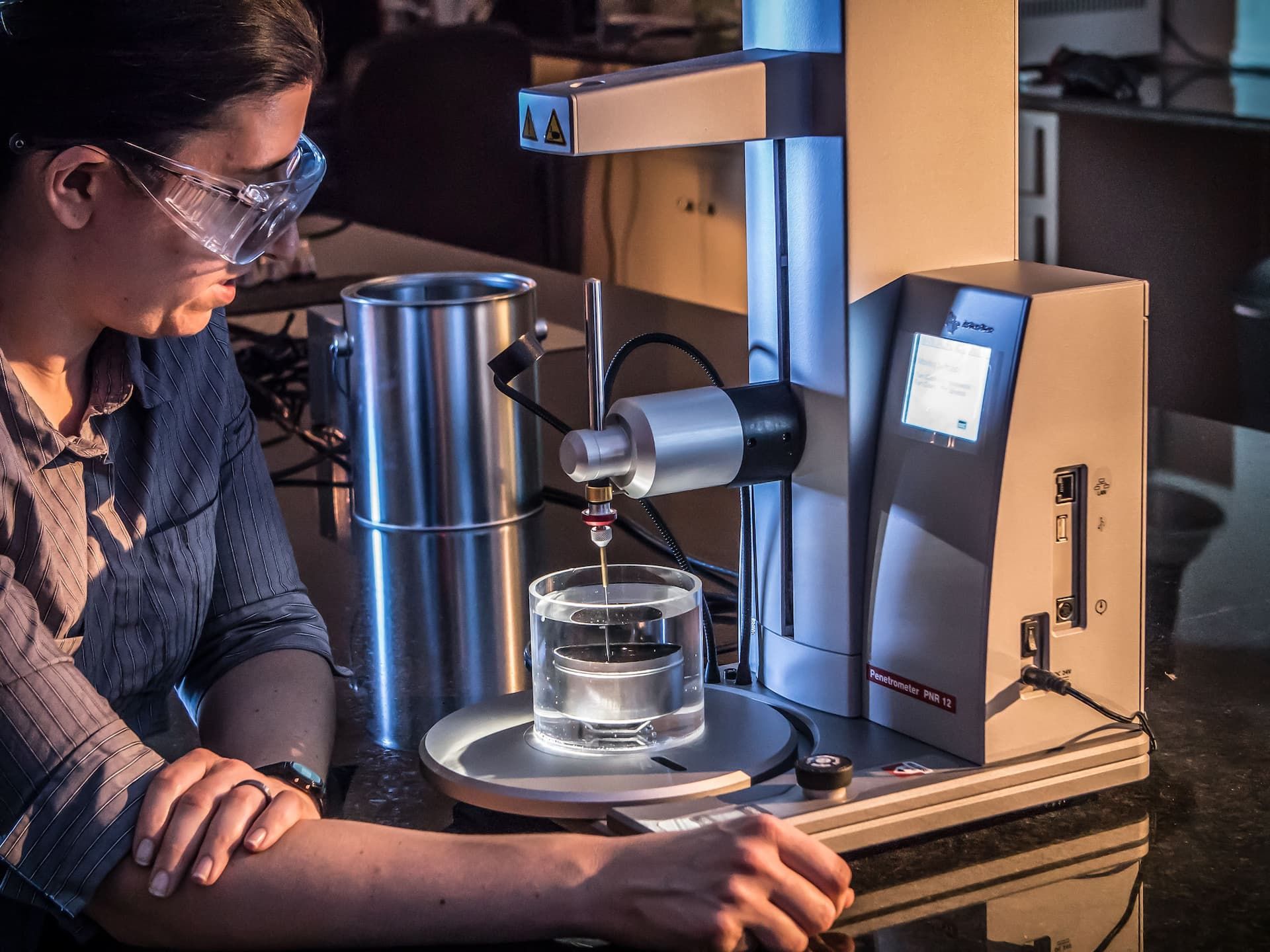 Industrial photo of an asphalt lab technician performing tests in a laboratory, emphasizing quality assurance in construction materials. Asphalt Lab Technician Working in Laboratory