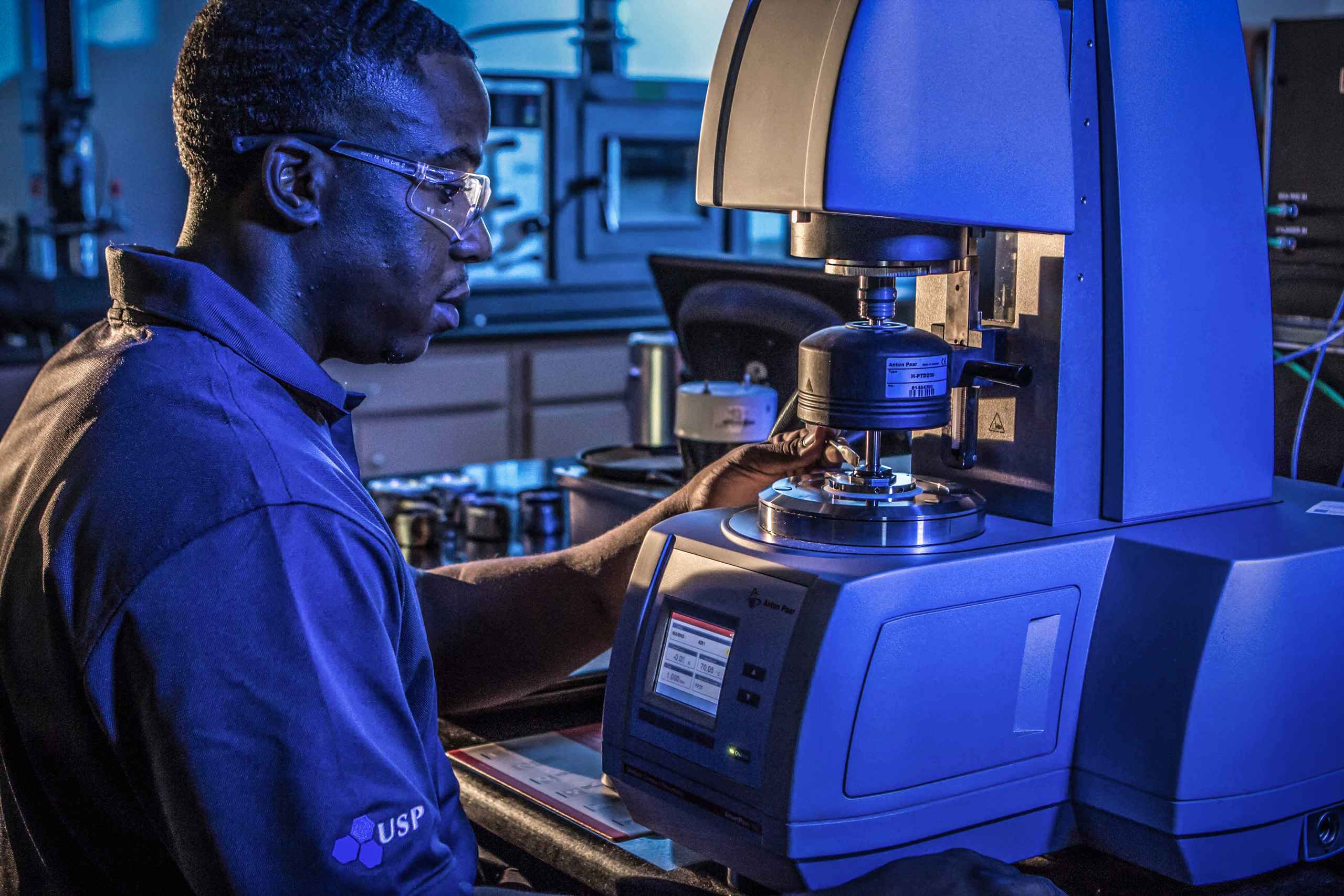 Industrial photo of a lab technician using testing equipment, highlighting accuracy and quality assurance in laboratory processes. Lab Technician Using Testing Equipment - Dallas Industrial Photography