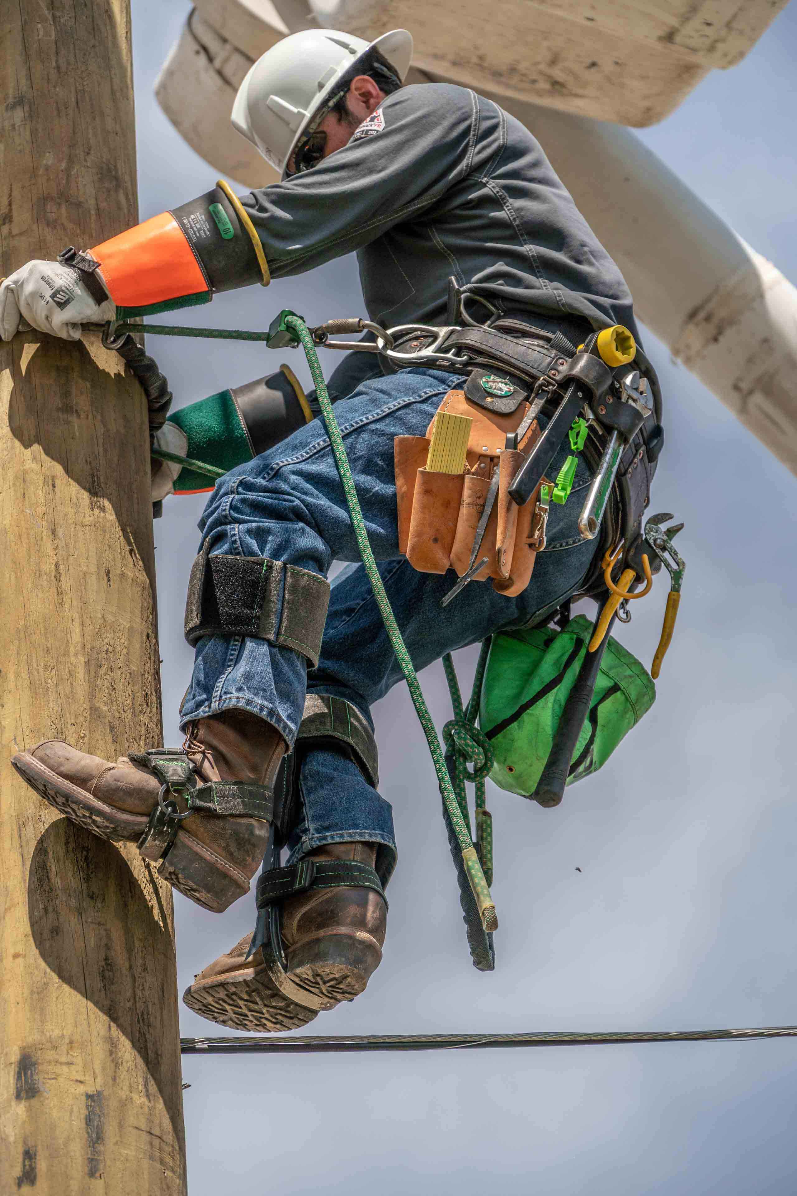 Industrial photo of a lineman climbing a telephone pole, highlighting expertise in utility maintenance and infrastructure support. Lineman Climbing Telephone Pole - Dallas Industrial Photography