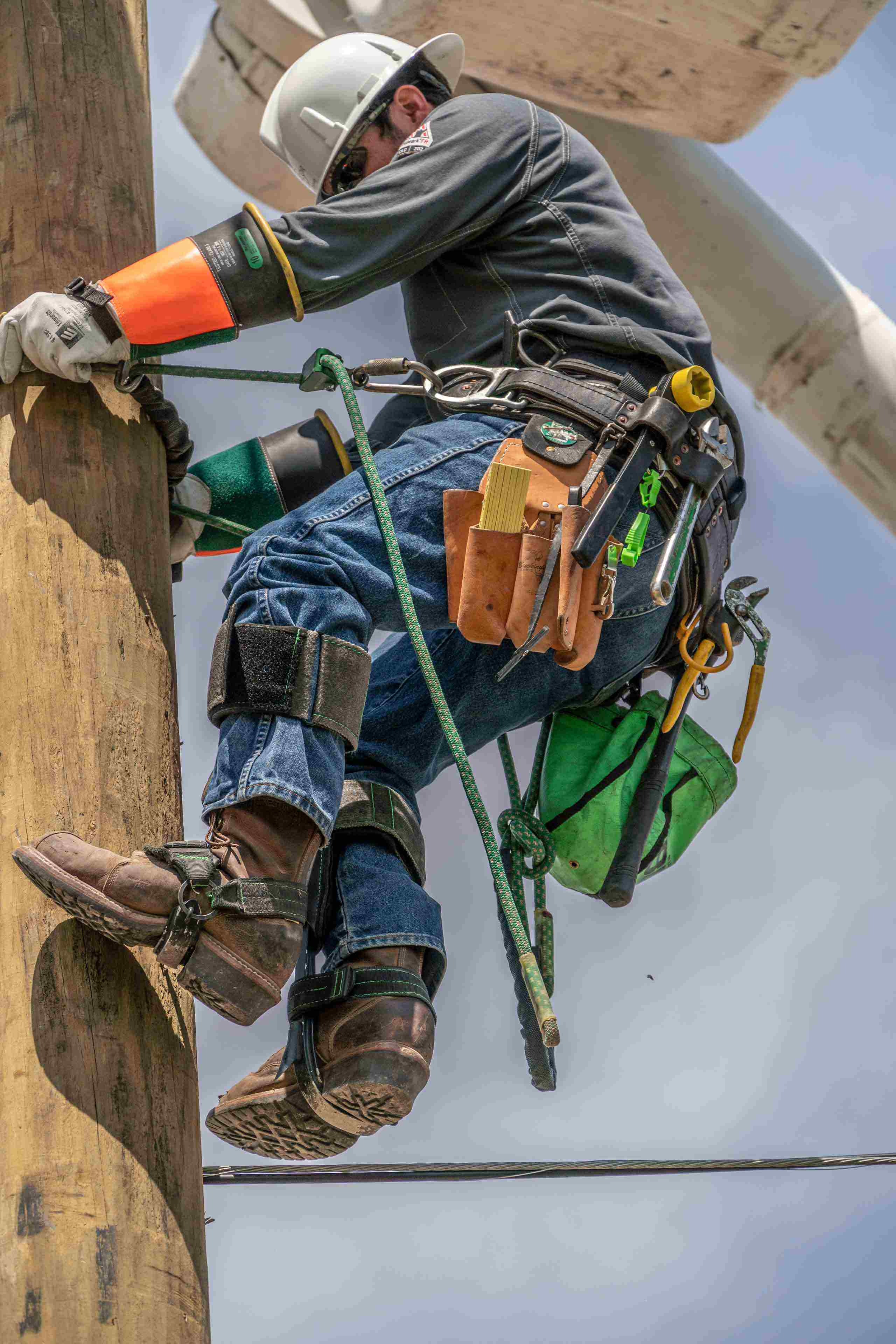 Industrial photo of a lineman climbing a telephone pole, highlighting expertise in utility maintenance and infrastructure support. Lineman Climbing Telephone Pole - Dallas Industrial Photography