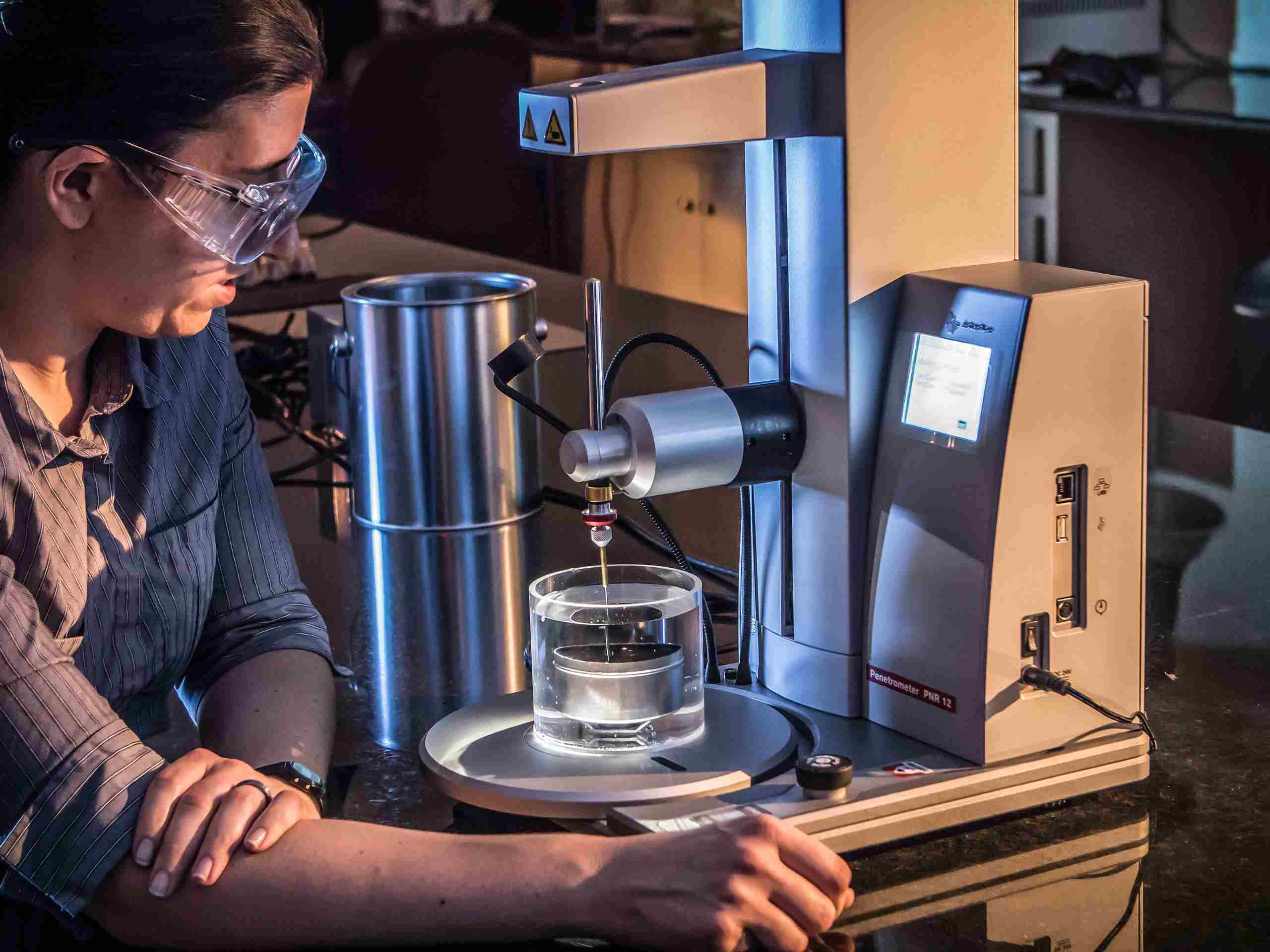 Industrial photo of an asphalt lab technician performing tests in a laboratory, emphasizing quality assurance in construction materials. Asphalt Lab Technician Working in Laboratory