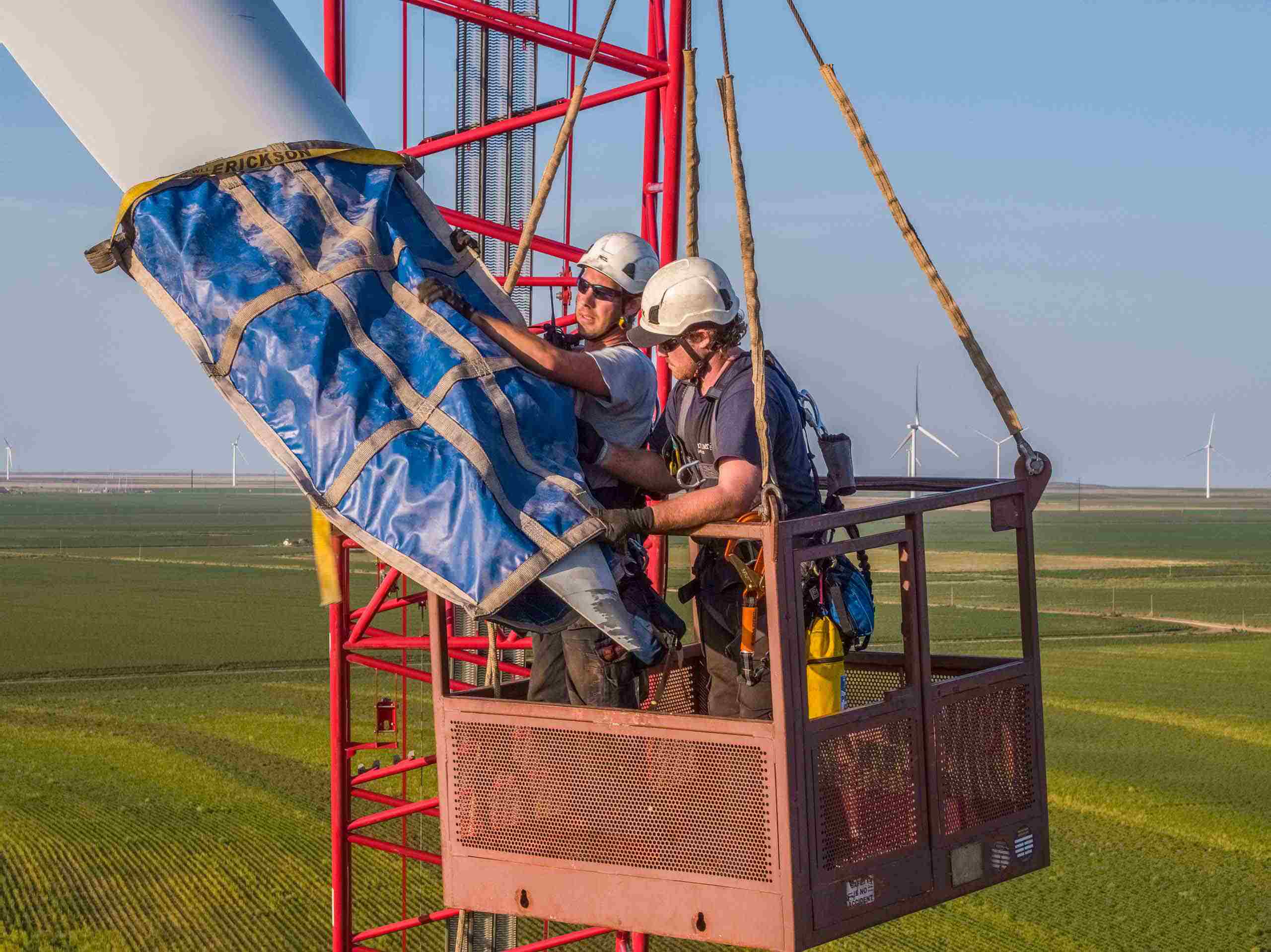 Drone aerial photo of a wind turbine technician securing the blades before removal, emphasizing safety and maintenance in renewable energy operations. Wind Turbine Technician Securing Blades - Drone Aerial View