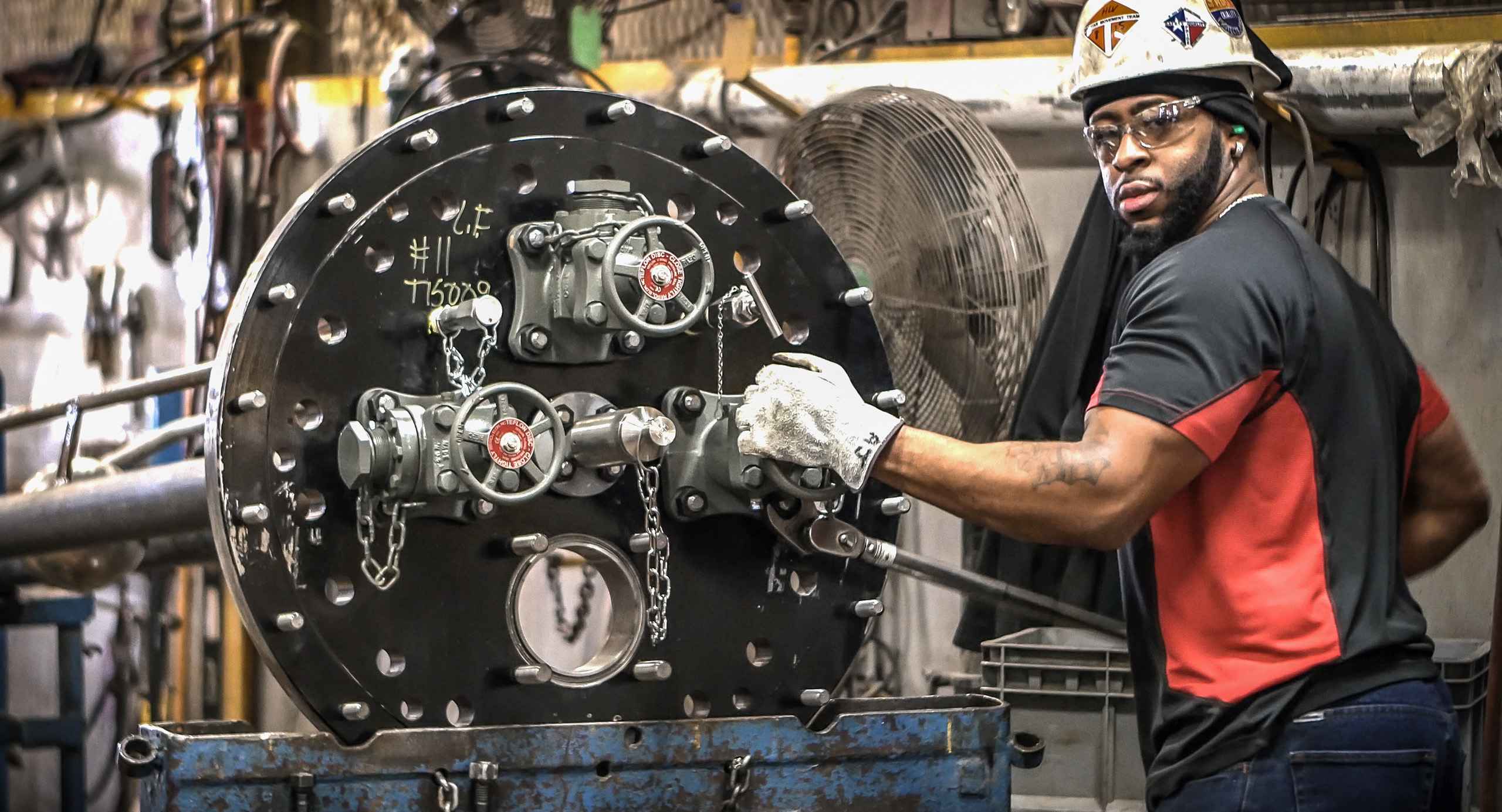 Industrial photo of a worker tightening fittings on a pressure tank car, emphasizing safety and maintenance in industrial settings. Tightening Pressure Tank Car Fittings - Dallas Industrial Photography