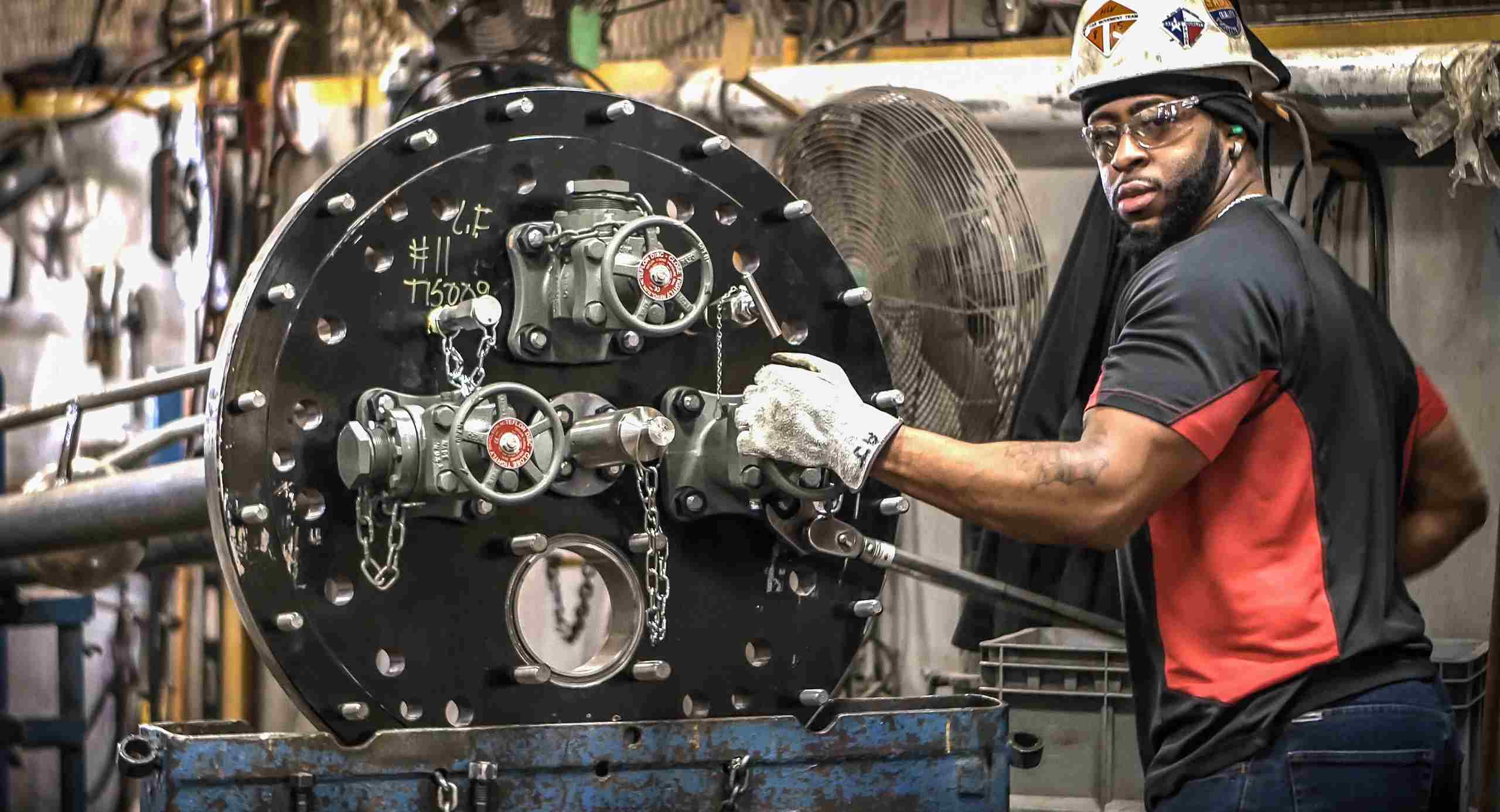 Industrial photo of a worker tightening fittings on a pressure tank car, emphasizing safety and maintenance in industrial settings. Tightening Pressure Tank Car Fittings - Dallas Industrial Photography