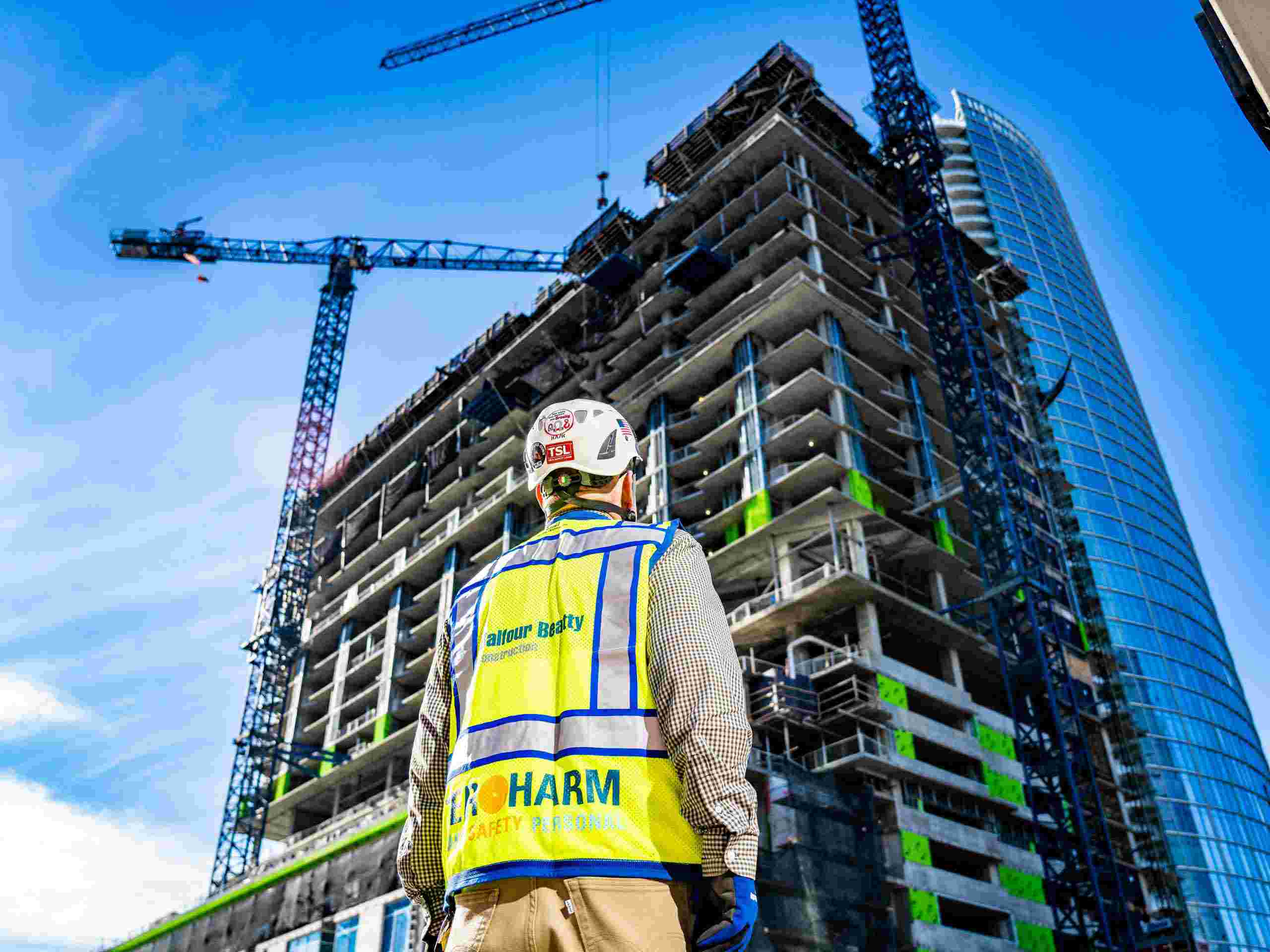 Mastering the Heights: Commercial Building Supervisor Gazing Up at Majestic Skyscraper