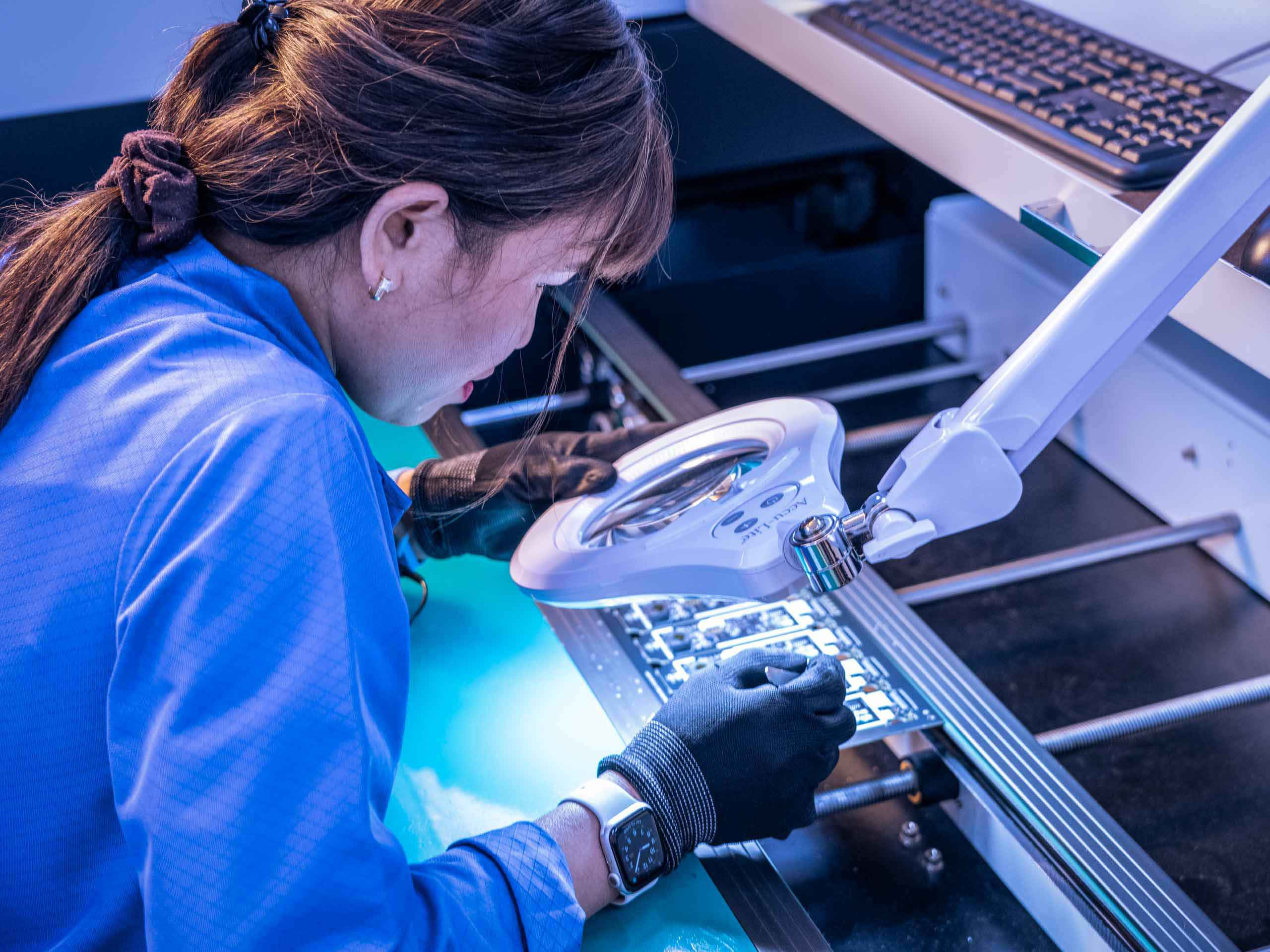Industrial photo of technicians inspecting motherboards for defects, emphasizing quality assurance in electronics production. Motherboard Inspection for Defects - Dallas Industrial Photography