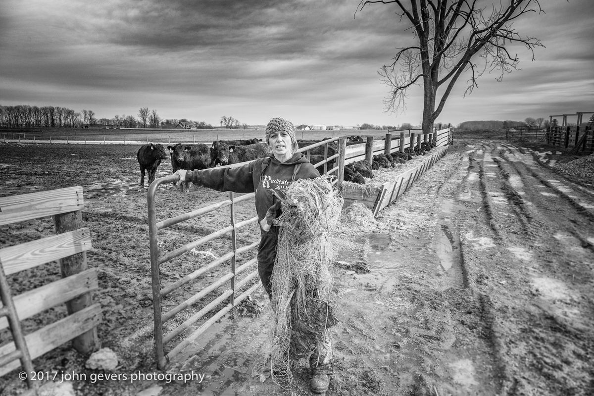 Cathy closes the gate to the pasture after gathering bale wrapping.