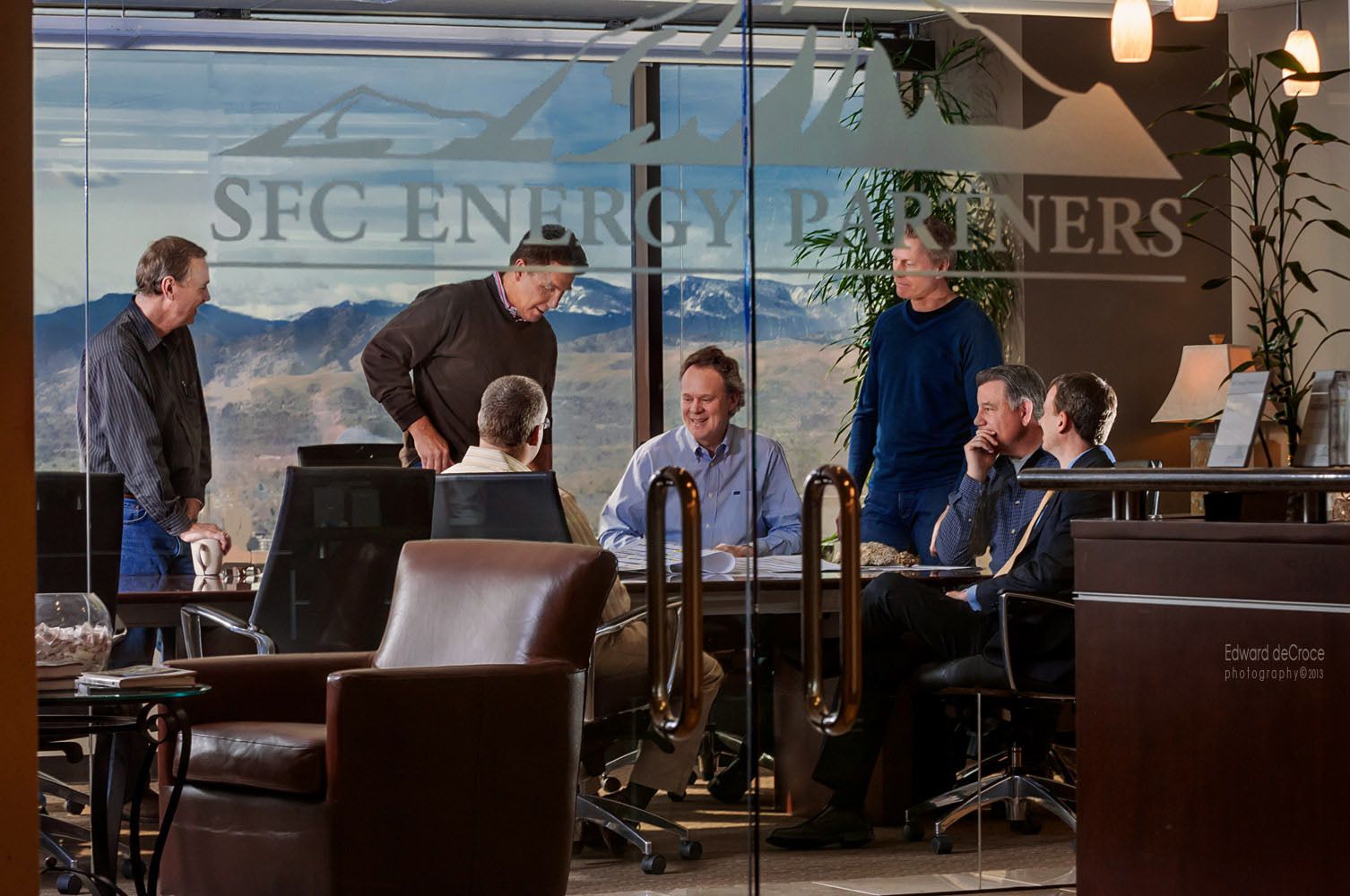 Natural meeting group action photography for Denver investment firm in office tower with mountain background.