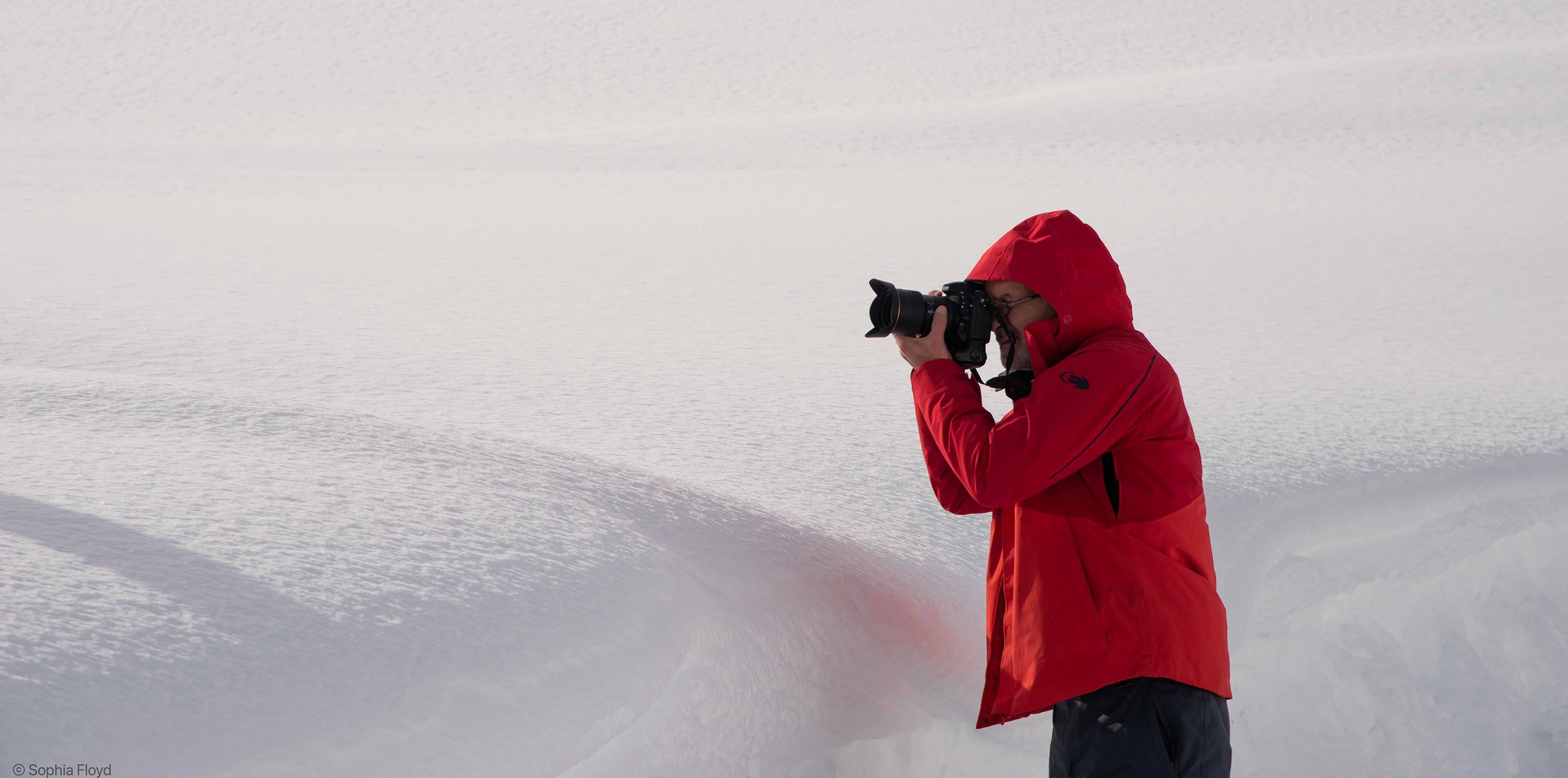 Professional travel advertising and lifestyle photographer is depicted in this image while photographing in deep snow. Photograph by Sophia Edward DeCroce - Professional Photographer