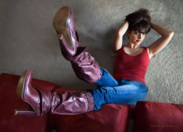 Denver model portfolio photographers and fasion photographers in Denver Colorado capture uncommon shots. The model rests on the floor with legs straight up toward the lens wearing fashion maroon boots in this model portfolio image. Fun Model Photography