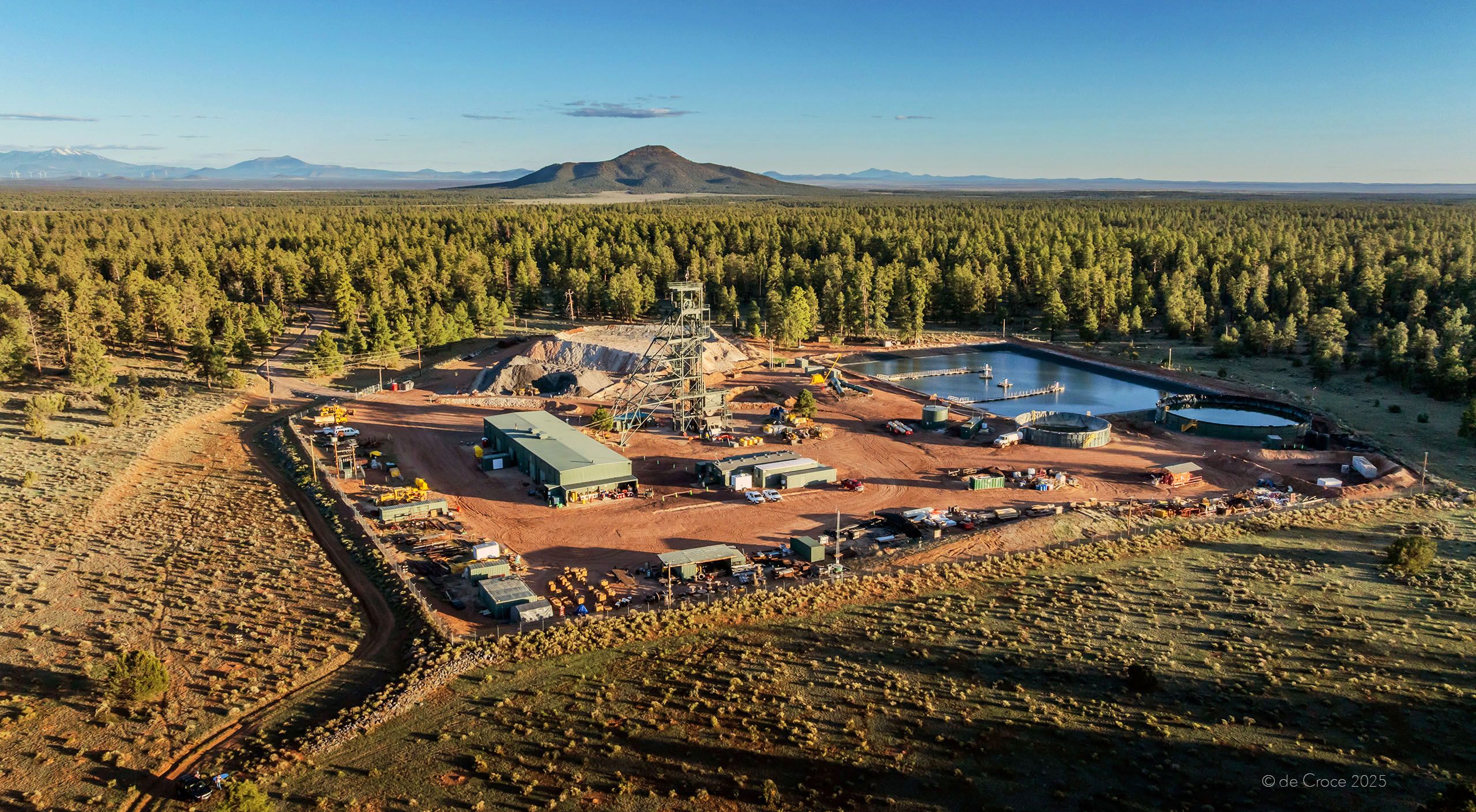 Commercial photographers traveled to Arizona for mining photoshoot. In this image, the surface structure for underground mining operations demonstrate industrial footprint. Late afternoon light illuminates forest and mine from aerial drone perspective. Aerial Mine Commercial - Grand Canyon, Arizona