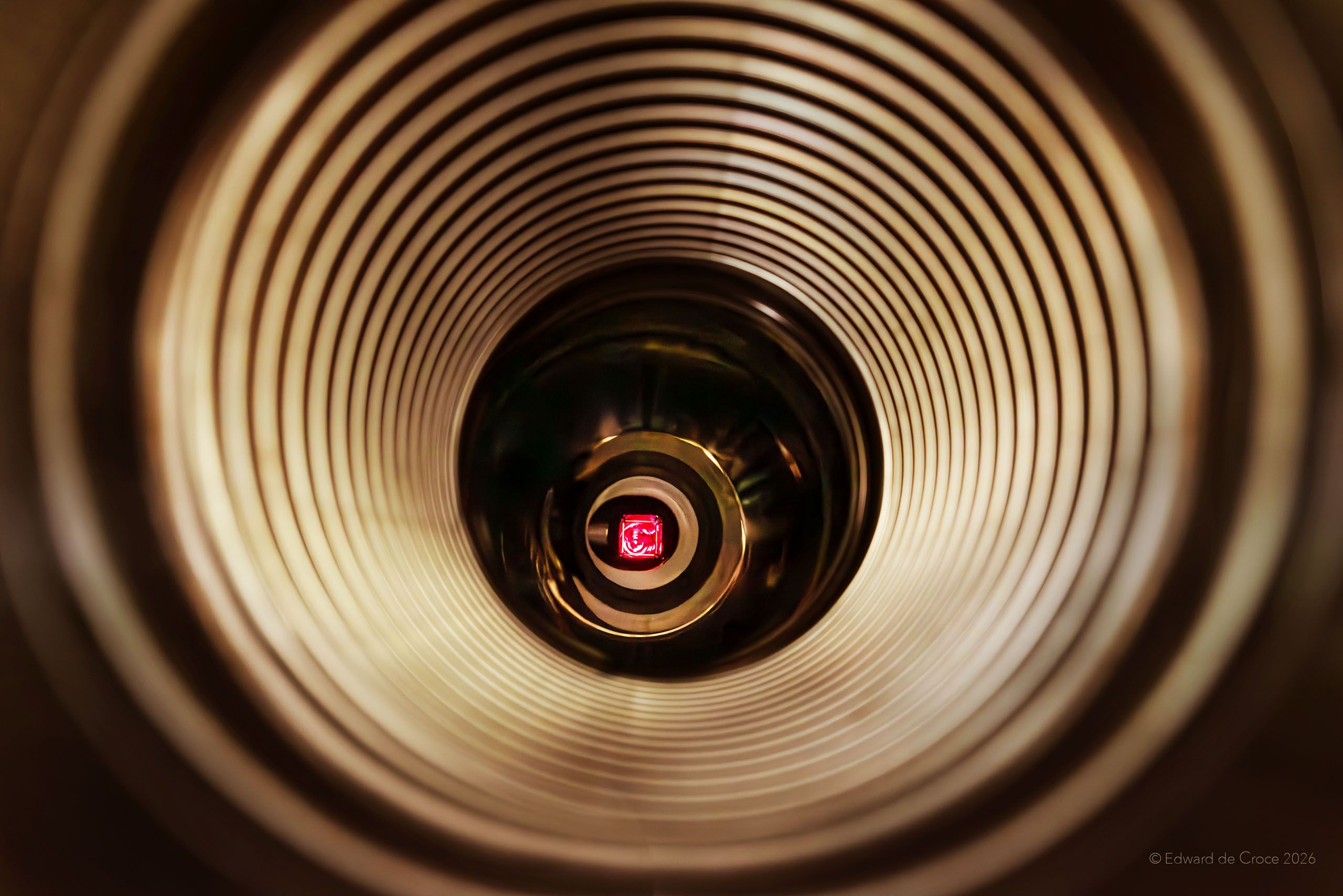 Looking down the long tunnel of laser research for nuclear fusion energy, American industrial photographer, Edward DeCroce crafts graphic imagery for Xcimer Energy Corporation in Denver Colorado. The photograph depicts circular light patterns inside the 500 feet long laser tube as the laser source is illuminated with red gel. Nuclear Fusion Energy Laser - Xcimer Energy - Denver Colorado. Photographed By American Industrial Photographer, Edward DeCroce