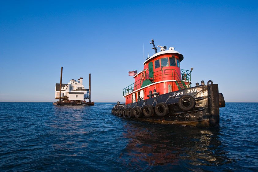 House being moved by a tugboat, on Long Island Sound.