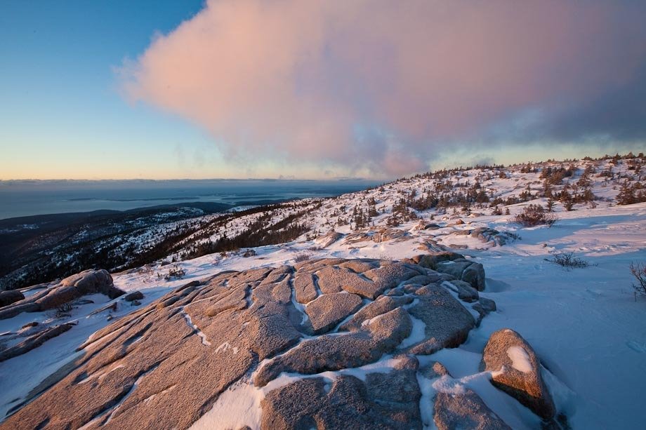 Sunrise on the summit of Cadillac Mountain in Acadia National Park after a winter storm.