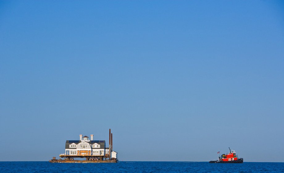 House being moved by a tugboat, on Long Island Sound.